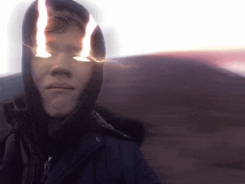 a man wearing a hooded jacket has a light shining through his eyes