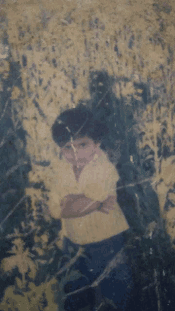 a boy in a yellow shirt is standing in a field