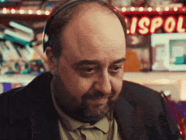 a bald man with a beard wearing headphones in front of a sign that says mispo