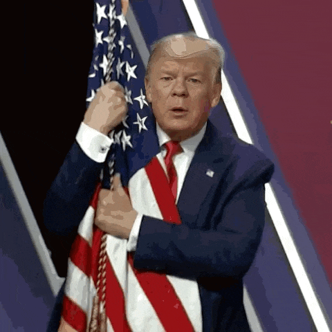 a man in a suit and tie holds an american flag in front of his chest