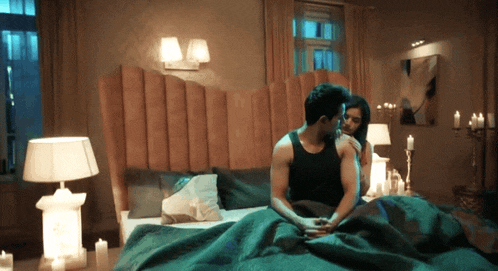 a man and a woman are sitting on a bed in a bedroom