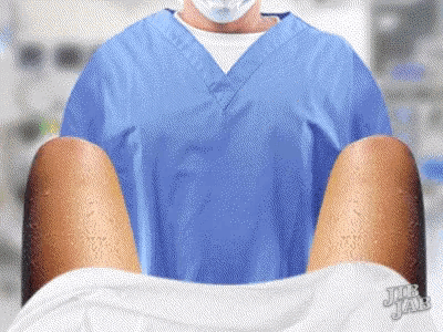 a man in a blue scrub is holding a woman 's legs in a hospital