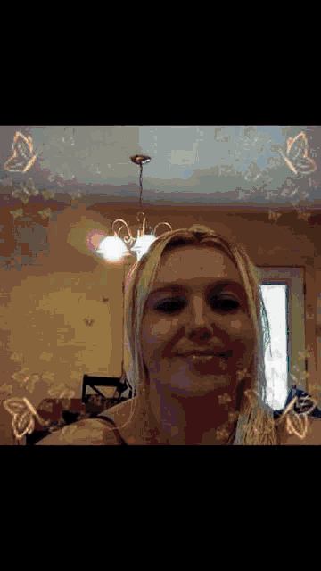 a woman is smiling in front of a chandelier with butterflies on the ceiling