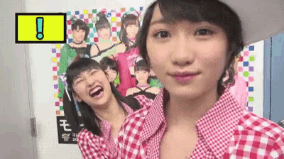 a girl in a plaid shirt is laughing in front of a poster of a girl .
