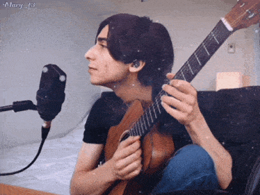 a man playing a guitar in front of a microphone with the name mary 43 on the bottom right