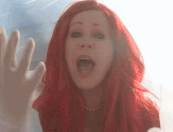 a woman with red hair is behind a glass
