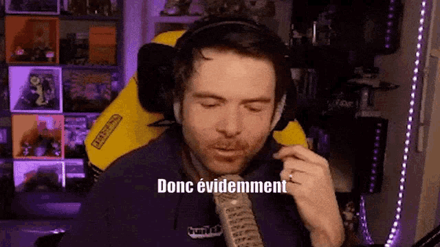 a man wearing headphones and a tie is talking into a microphone with the word donc evidemment written on the screen