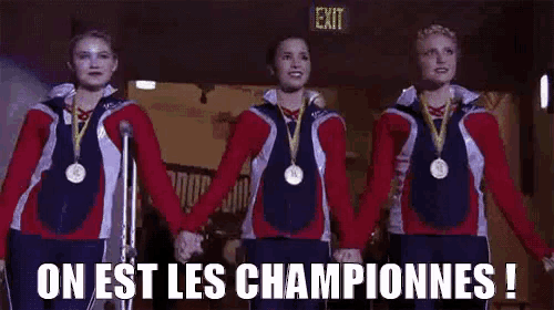 a group of female gymnasts are holding hands in front of a microphone while wearing medals .