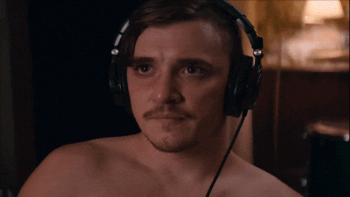 a man without a shirt is wearing headphones and looking at the camera