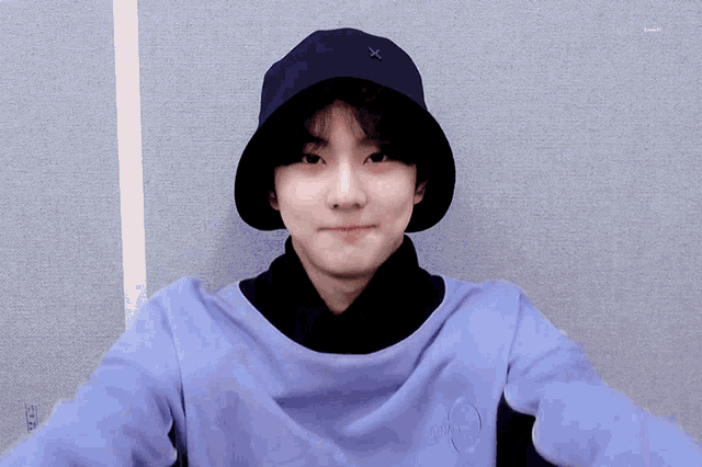 a young man wearing a hat and a purple shirt with a circle on the front