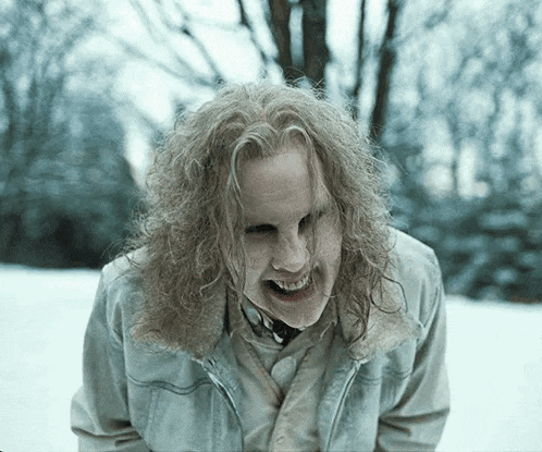 a man with long curly hair is making a face in the snow