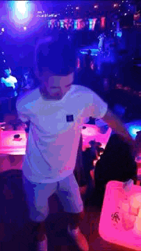 a man in a white shirt is dancing in a nightclub