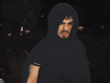 a man in a black hooded cape with a red stripe on his face