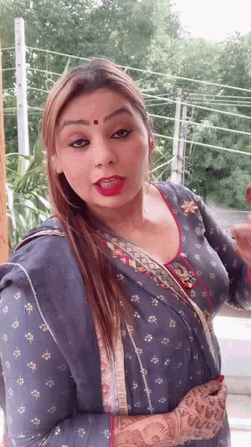 a woman with a red dot on her forehead is wearing a blue and white dress