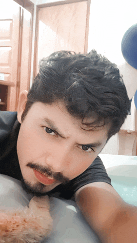 a man with a beard is laying on a bed and taking a selfie
