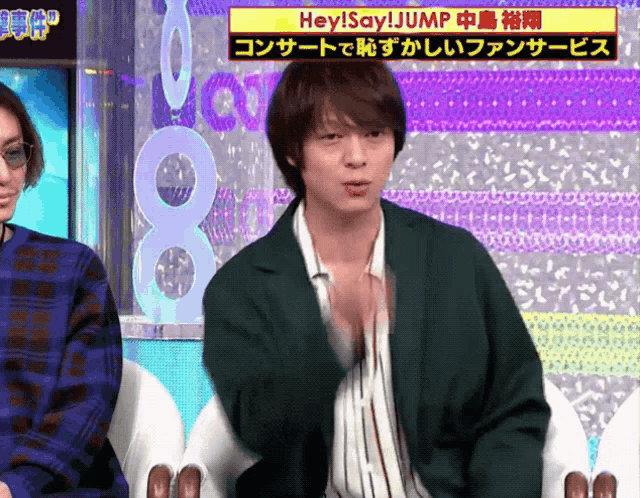 a man in a green jacket is sitting in front of a sign that says hey ! say ! jump