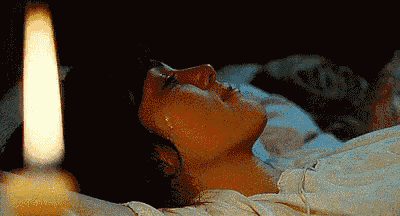 a woman is laying on a bed with a candle in front of her