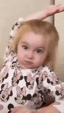 a baby girl is wearing a minnie mouse pajama set and making a funny face .