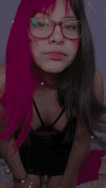 a girl with pink hair and glasses is pointing at something