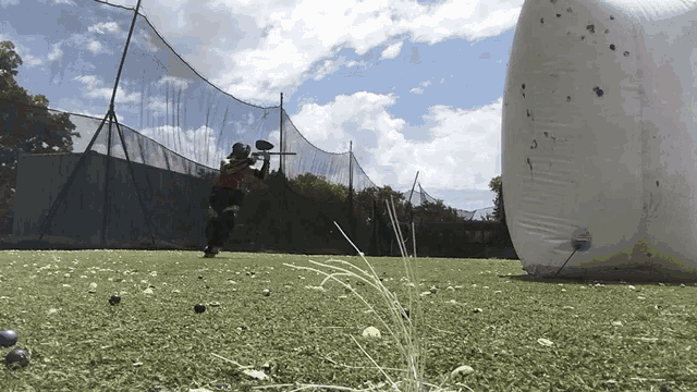 a person is playing paintball in a field with a white ball in the background