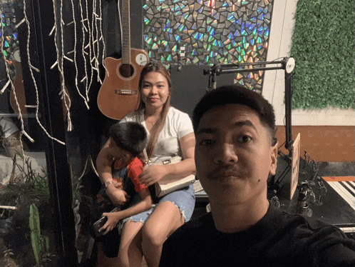 a man and a woman are posing for a picture in front of a guitar that has the letter a on it