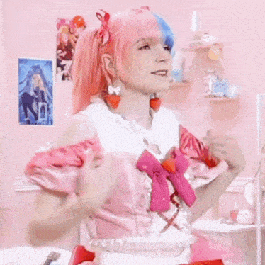 a woman with pink and blue hair is wearing a pink dress with a bow on it .
