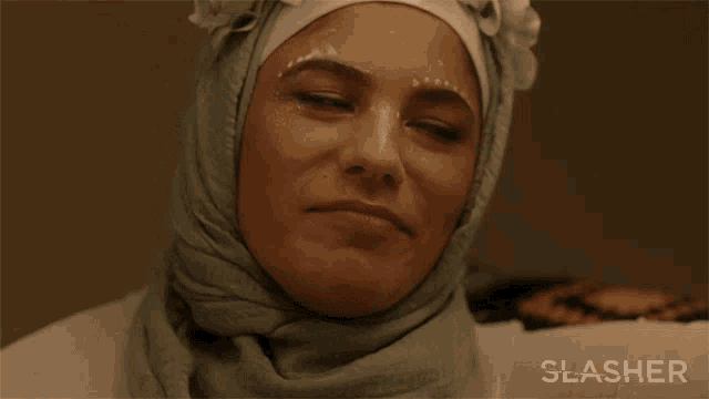 a woman wearing a hijab with a flower on her head and the word slasher in the corner