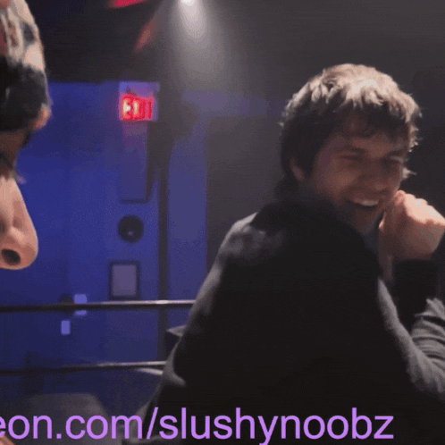 a blurry photo of a man laughing with the website slushynoebz in the corner
