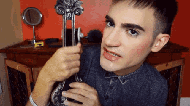 a man in a grey shirt is holding a metal object in his hands