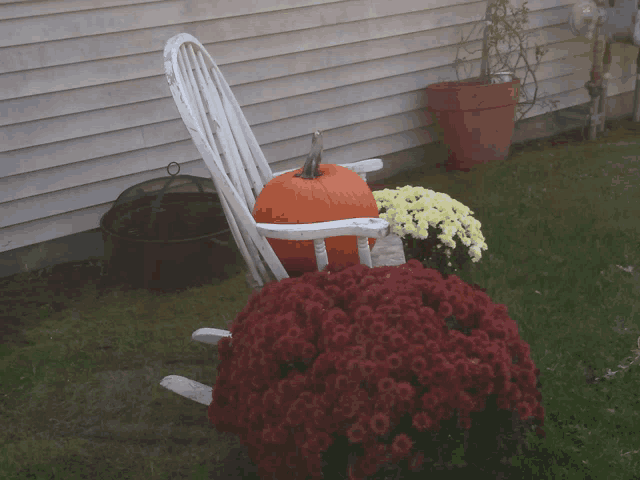 a white rocking chair with a pumpkin and flowers on it