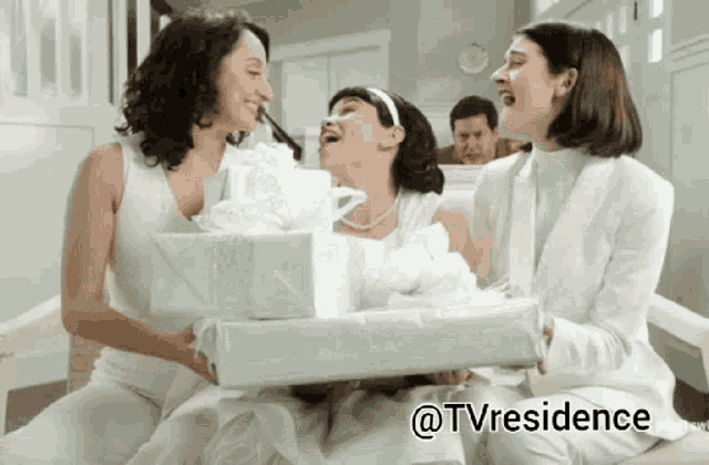 three women in white are holding white gifts and the words @tvresidence are on the bottom
