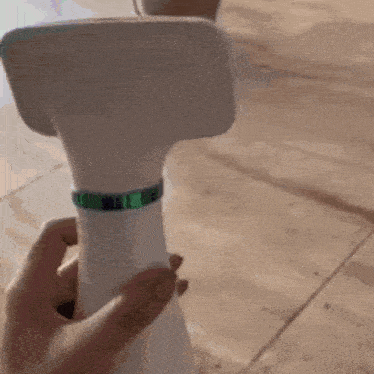 a person is holding a white bottle with a green band around it .