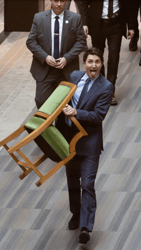 a man in a suit and tie is carrying a chair