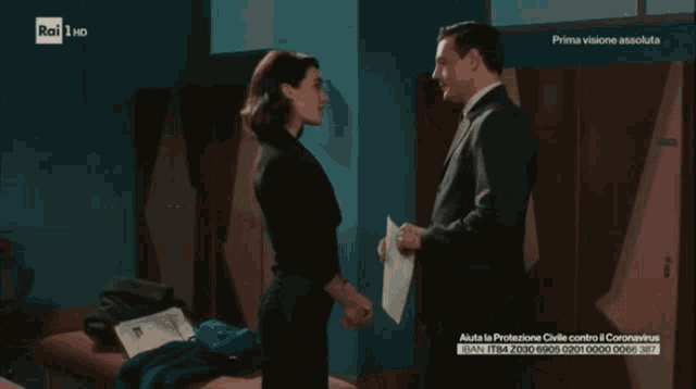 a man in a suit and a woman in a black dress are standing next to each other on a rai 1 hd screen