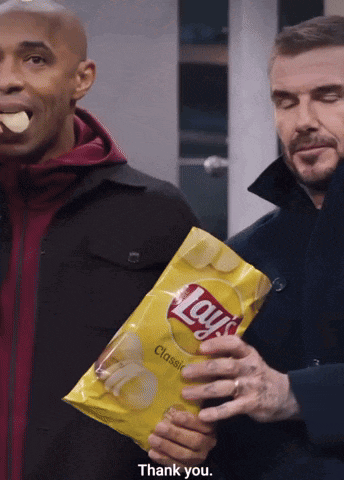 a man is holding a bag of lays chips and another man is eating chips