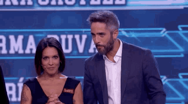 a man and a woman are standing next to each other in front of a sign that says ' ama uva '