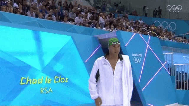 a man in a white jacket is standing in front of a large screen that says chad le clos rsa