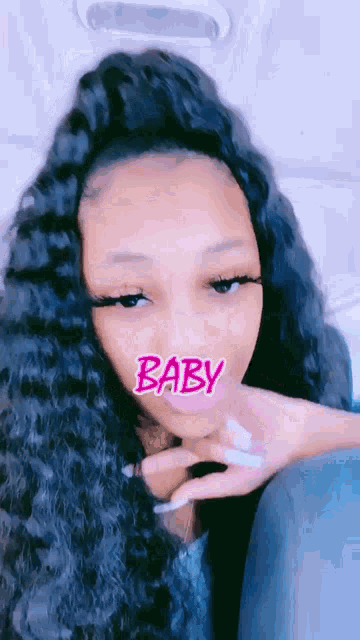 a woman with long black hair is wearing a pink mask that says baby .