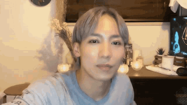 a young man with gray hair is taking a selfie in front of a desk
