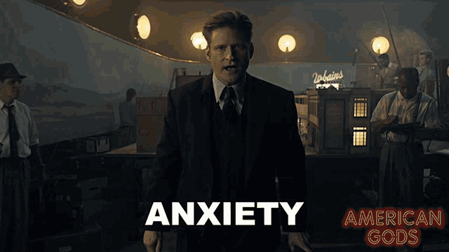 a man in a suit and tie is standing in front of a sign that says anxiety