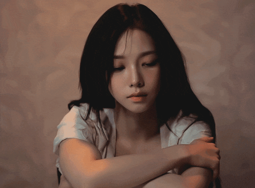 a woman with long black hair and a white shirt looks down