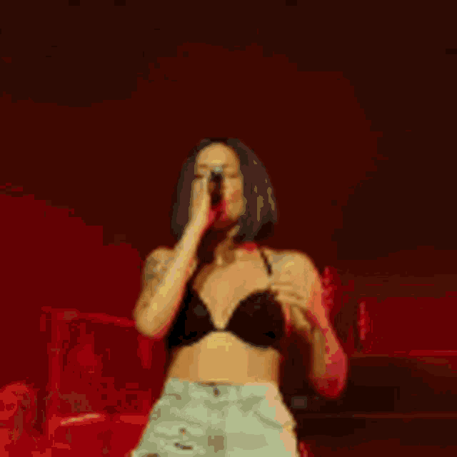 a woman in a crop top and shorts is dancing on a stage .