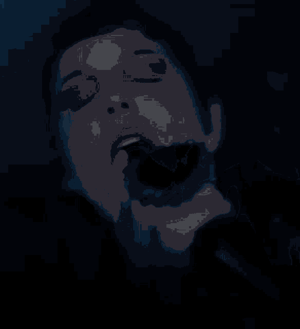 a close up of a woman singing into a microphone in a dark room