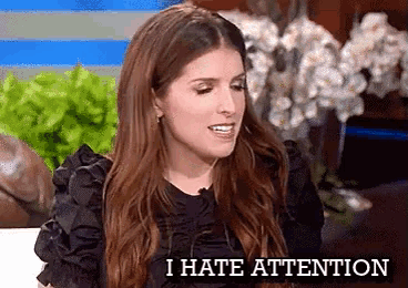 a woman is sitting in front of a microphone with the words `` i hate attention '' written on the screen .