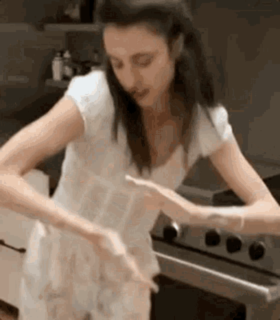 a woman is standing in front of a stove in a kitchen and cooking .