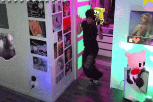 a person is dancing in a room with a kirby doll on the wall