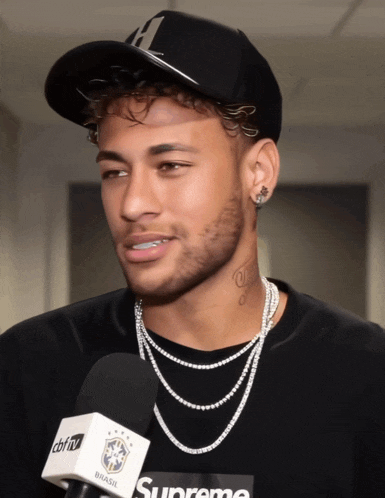a man wearing a black shirt that says supreme is talking into a microphone