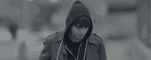a man wearing a black hoodie and headphones is walking down a street .