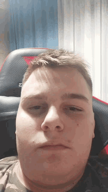 a man is sitting in a chair and making a funny face with his eyes closed