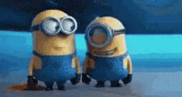 two minions are standing next to each other on the beach .